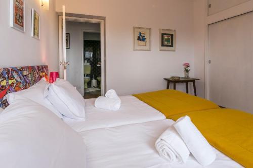 a bedroom with a large white bed with a yellow blanket at Apartamento Vintage 2 in Porto