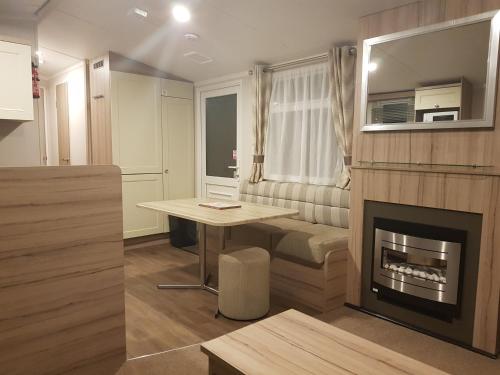 a living room with a table and a fireplace at Sunnyvale Holiday Park in Saundersfoot