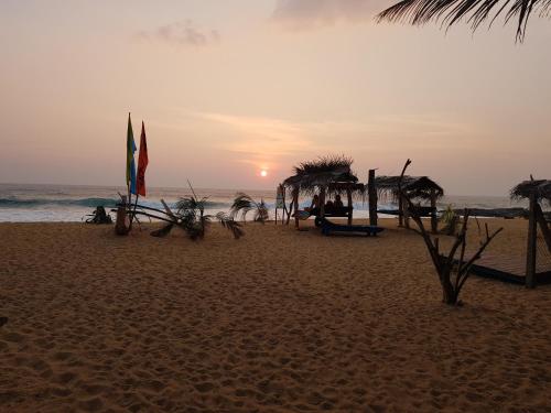 a beach with umbrellas and the ocean at sunset at Dreamvillage in Dodanduwa