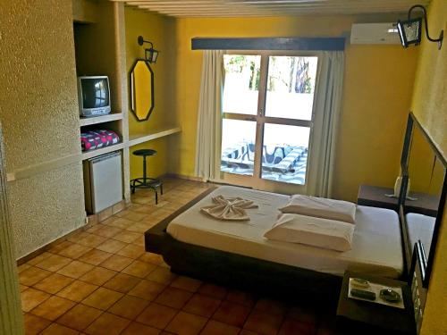 a bedroom with a large bed and a window at Hotel Comodoro de Rosário Do Sul in Rosário do Sul