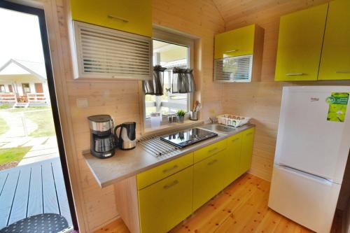 a kitchen with yellow cabinets and a white refrigerator at Ośrodek Wypoczynkowy Lawendowo in Jarosławiec