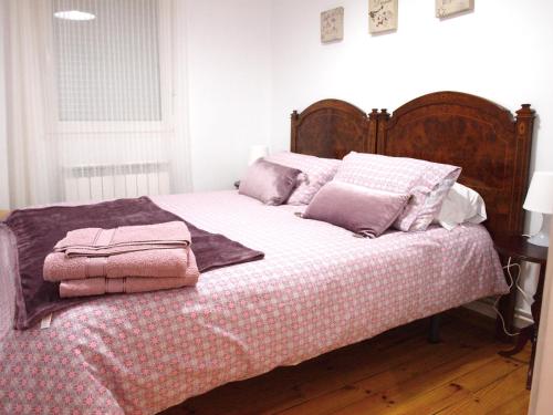 Una cama con mantas rosas y almohadas. en Piso Madrazo, en León
