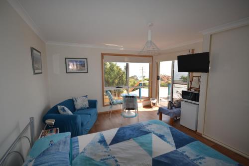 a bedroom with a bed and a living room at Seascape Beach House in Boat Harbour