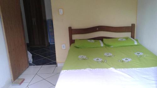 a bed with green sheets and green pillows on it at Casa em Arraial d'Ajuda in Arraial d'Ajuda