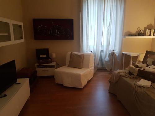 sala de estar con silla blanca y TV en Appartamento Gradisca, en Lecco