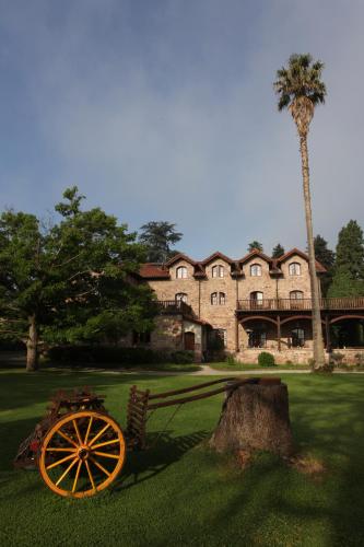 a large house with a tree and a wooden cart at Jardin de Carrejo in Cabezón de la Sal