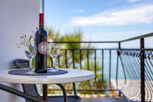 a bottle of wine sitting on a table with two glasses at Rooms Marinac in Podstrana