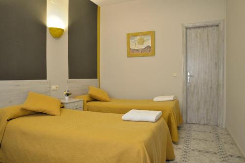 two beds in a room with yellow sheets at Cuatro Caminos in Piedrabuena