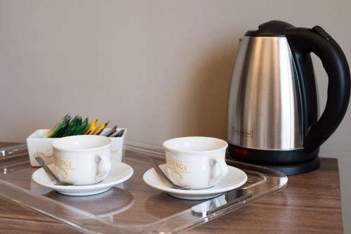 a tray with three cups and a coffee pot at 7th Floor Suite in Naples