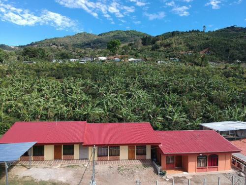 ein Haus mit rotem Dach vor einem Hügel in der Unterkunft Casa en zona tranquila y rural in Higueronal
