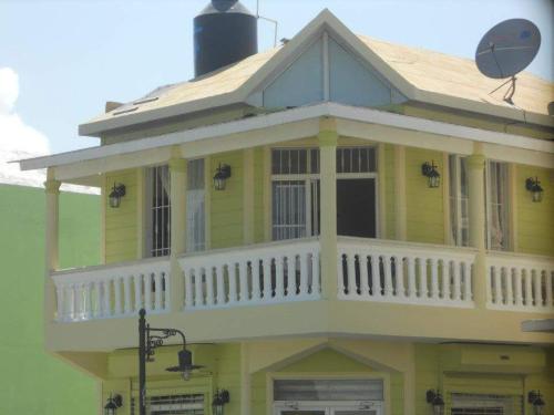 a yellow house with a porch and a balcony at Apartamento Frente Al Mar in San Felipe de Puerto Plata