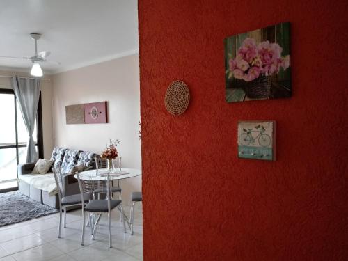 sala de estar con pared roja, sofá y mesa en Ap da Cris, en Torres