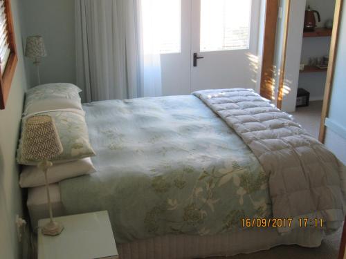 una camera da letto con un letto con una coperta e un tavolo di Woolshed Bed & Breakfast a Takaka