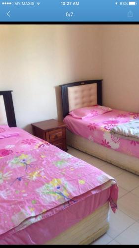 two beds in a room with pink sheets on them at Sunshine Bay Resort Port Dickson in Port Dickson