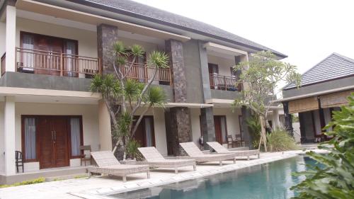 a resort with chairs and a swimming pool at Jonsen Homestay in Canggu