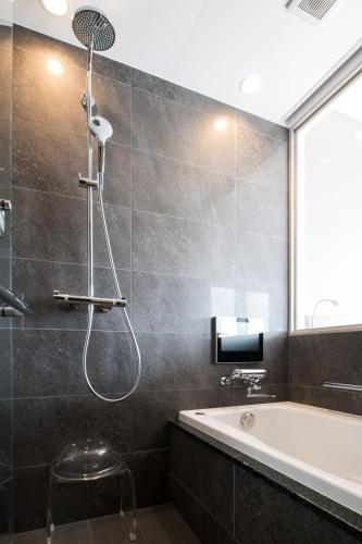 a bathroom with a shower and a bath tub at Piazza Hotel Nara in Nara