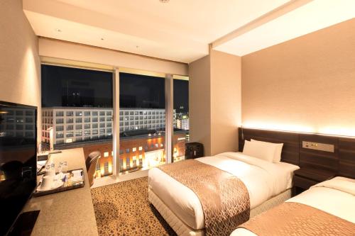 a bedroom with two beds and a window with a view at Piazza Hotel Nara in Nara