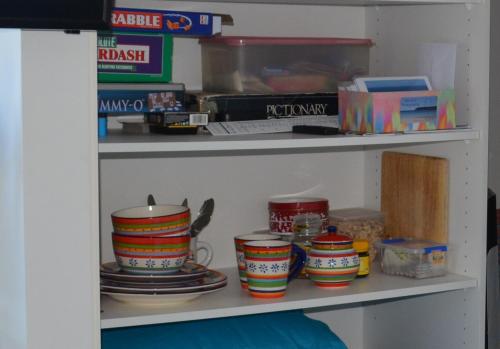 Seascape Beach House في بوت هاربور: رف مع أكواب ملونة وأطباق عليه