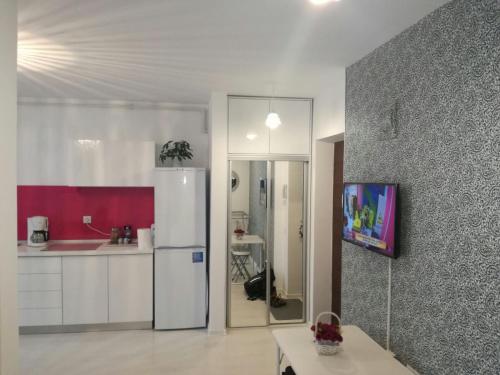 a kitchen with a white refrigerator and a red wall at White Luxury Apartment in Sibiu