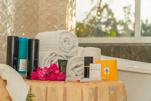 a pile of towels and flowers on a table in a bathroom at Tea Hills Bungalow in Hatton