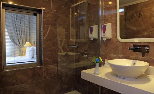 Roseira Beach Resort في غولوك: حمام مع حوض ودش زجاجي