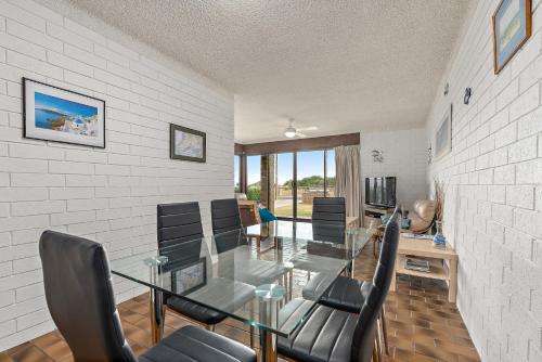 Aldinga Beach的住宿－阿爾丁加海灘太陽與衝浪公寓，一间设有玻璃桌和椅子的用餐室