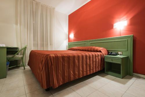 ein Schlafzimmer mit einem Bett mit einer roten Wand in der Unterkunft Hotel Villa Molinari in Collecchio