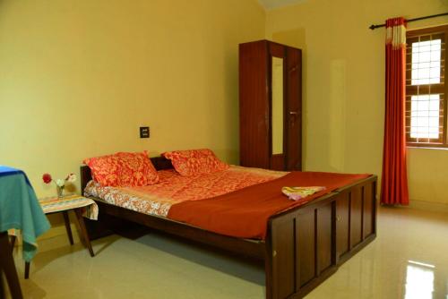 a bedroom with a large bed with orange sheets and red pillows at Nandanam Villa in Kaniyāmbetta