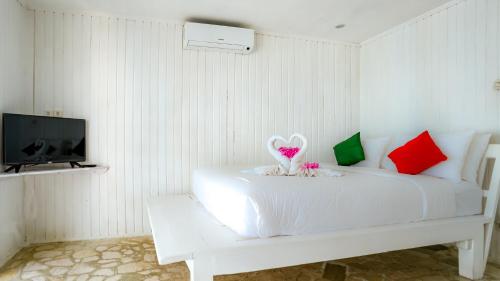 Dormitorio blanco con cama blanca y almohadas rojas y verdes en Balatoa, en Bira