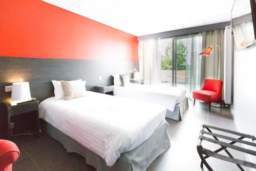 a hotel room with two beds and a red wall at Hôtel du Casino de Capvern in Capvern