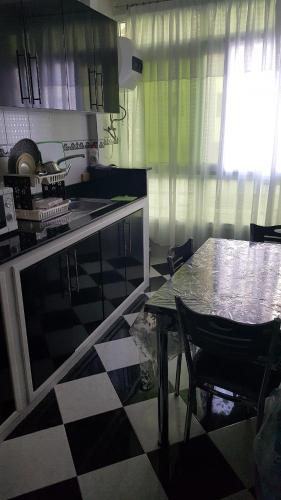 a kitchen with a table and a checkered floor at Addoha Apartment in Tangier