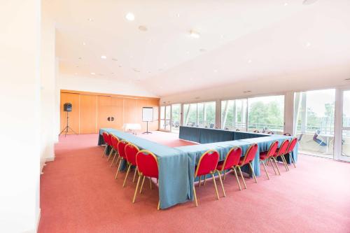 a conference room with a long table and red chairs at Hôtel du Casino de Capvern in Capvern