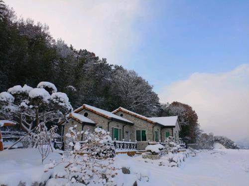 una casa cubierta de nieve frente a un bosque en Chungaram, en Damyang