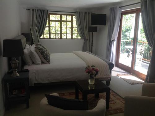 a bedroom with a bed and a window and a couch at Willow Brooke Guest Suite in Franschhoek