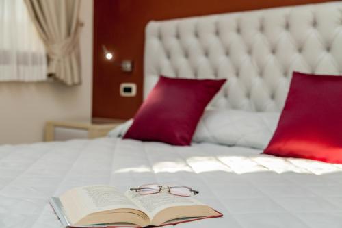 a book and glasses sitting on top of a bed at Hotel Sa Cheya Relais & Spa in Alghero