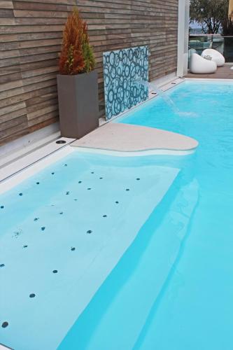 a blue swimming pool with a chair next to it at Hotel Villa Paola in Rimini