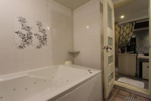 a white bath tub in a white bathroom at Hera Hotel in Daegu