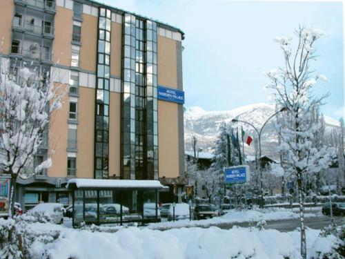 un grand bâtiment avec de la neige devant lui dans l'établissement Hotel Norden Palace, à Aoste