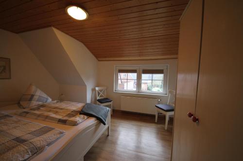 a small bedroom with a bed and a window at Pension Sturmmöwe in Norddorf