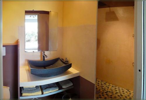 La salle de bains est pourvue d'un lavabo bleu et d'un miroir. dans l'établissement Gite La Gourmandine, à Saint-Andiol