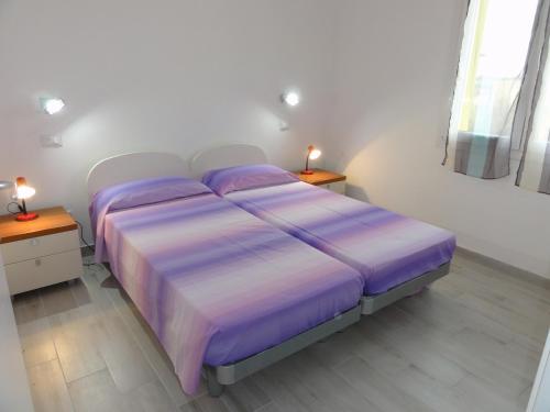 ビビオーネにあるSan Marco - Appartamentiのベッドルーム1室(紫色のベッド1台、ナイトスタンド2台付)