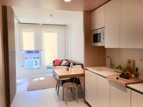 a kitchen with white cabinets and a table and a window at Inside Bilbao Apartments in Bilbao