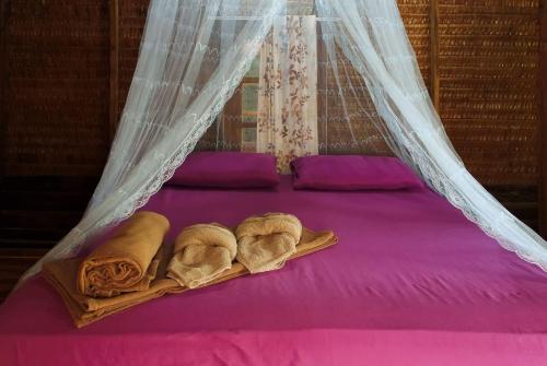 Una cama con dosel y toallas. en Rakkan Resort en Ko Phra Thong