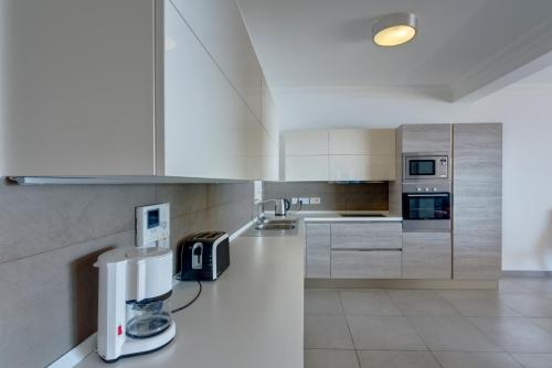a kitchen with white cabinets and a appliance on the counter at Seafront Apartment Sliema in Sliema