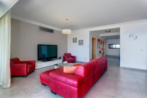 a living room with a red couch and a tv at Seafront Apartment Sliema in Sliema