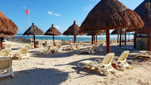 a group of chairs and umbrellas on a beach at Quetzal Apartment in Akumal