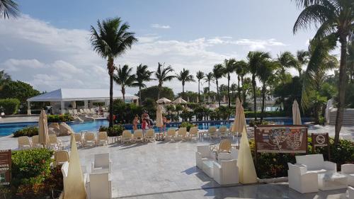 a resort with a pool and chairs and palm trees at Quetzal Apartment in Akumal