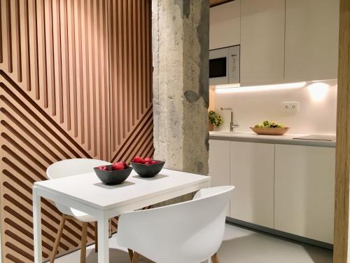 a kitchen with a white table and white chairs at Inside Bilbao Apartments in Bilbao