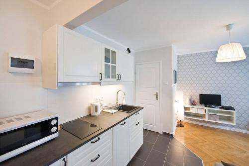 a white kitchen with a sink and a microwave at River Side Apartment Old Town in Gdańsk