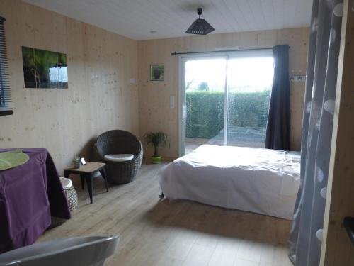 a bedroom with a bed and a sliding glass door at La cabane du Bonheur in Les Herbiers